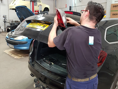 Our mechanic inspects rear lens unit on Vauxhall Astra Mechanic looking at rear light unit